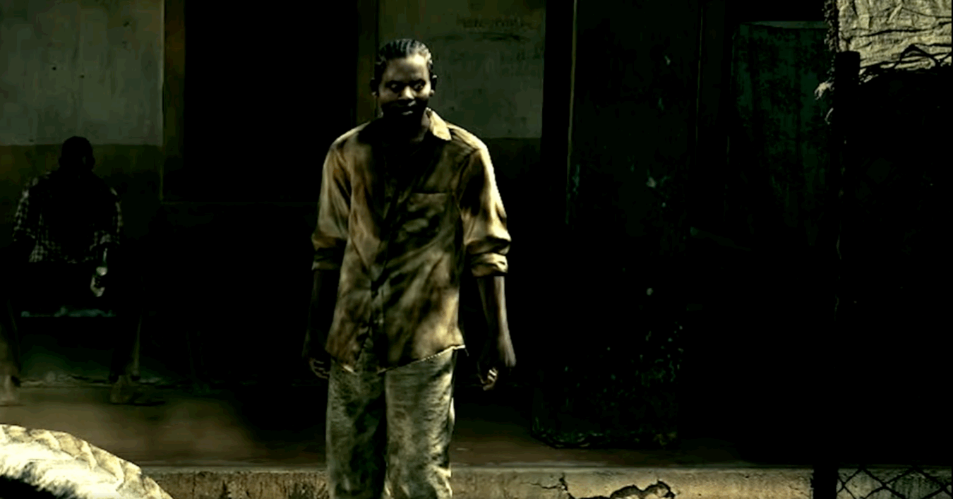 From a video game, a youn man stands appearing as a zombie and threatening.  
